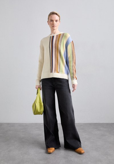 Knit sweater in cream with multicolored vertical stripes; paired with wide-leg black jeans and a lime green bag; brown shoes.