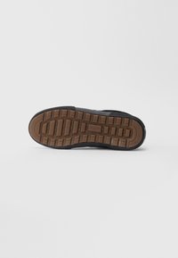 Podešev černé boty s hnědým gumovým vzorem a viditelným logem "GLOBE" ve středu.