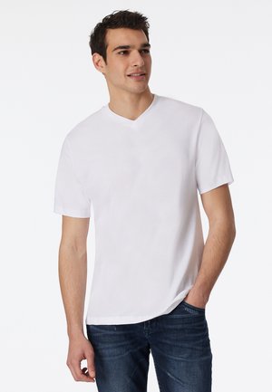 Weißes V-Ausschnitt-T-Shirt aus weicher Baumwolle, mit kurzen Ärmeln und lockerer Passform, kombiniert mit dunklen Jeans.