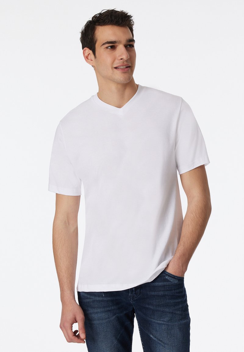 Hvid V-hals t-shirt lavet af blød bomuld, med korte ærmer og en afslappet pasform, parret med mørk denim jeans.