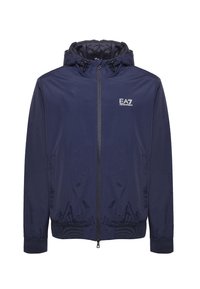 Marineblå vindjakke med lynlås foran, elastiske manchetter og justerbar hætte. EA7-logo på brystet, glat tekstur, letvægtsmateriale.