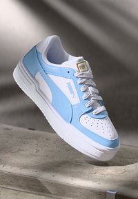 Világoskék és fehér sneaker, szintetikus bőrből készült; perforált orral, texturált részletekkel és fehér fűzőkkel rendelkező; Puma logóval a nyelvén.