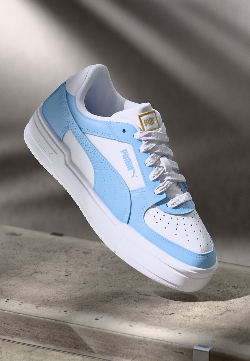Világoskék és fehér sneaker, szintetikus bőrből készült; perforált orral, texturált részletekkel és fehér fűzőkkel rendelkező; Puma logóval a nyelvén.