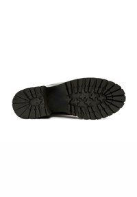 Suela de zapato de goma negra con profundas ranuras y patrones en forma de estrella para mayor tracción. Diseño plano y robusto con superficie texturizada.