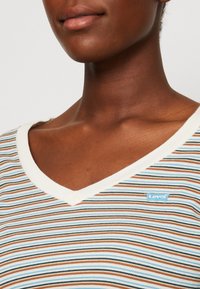 Gestreiftes kurzärmeliges V-Ausschnitt-T-Shirt in Weiß, Hellblau, Orange und Schwarz. Mit einem hellblauen Levi's-Logo auf der Brust. Material aus Baumwollmischung.