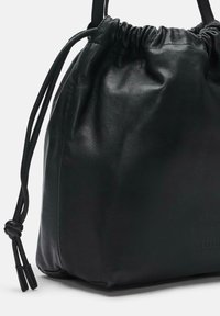 Borsa a tracolla nera in pelle con una consistenza morbida, forma arrotondata e dettagli annodati sulle cinghie. Branding discreto sul lato.