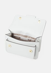 Hvid læder crossbody taske med guldsnaplukninger, åben klap der afslører en beige stofforingslomme mærket Michael Kors.