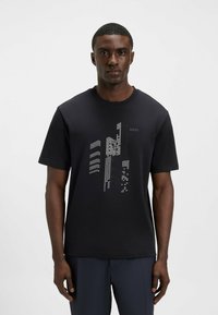 Black cotton t-shirt with short sleeves, featuring a printed geometric design in white, including text "BOSS." Crew neck style, regular fit.