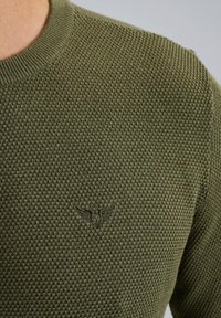 Maglione lavorato a maglia verde oliva con un motivo testurizzato, dotato di un collo a giro e di un logo ricamato discreto sul petto.