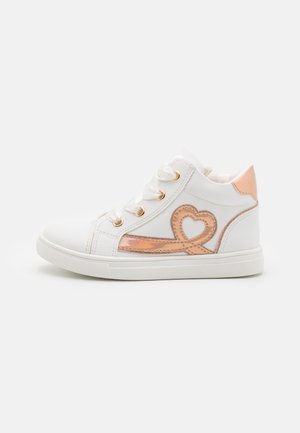 Zapatillas altas blancas con ojales dorados, un diseño de corazón en rosa dorado brillante en el costado y una suela de goma texturizada.