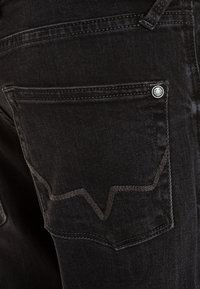 Czarne dżinsy denimowe z tylną kieszenią z kontrastowym przeszyciem w wzór zygzaka oraz srebrnym guzikiem z logo.