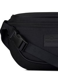 Fekete szövet övtáska cipzárral, sima tapintású, állítható pánttal és műanyag csattal. Jellemzi egy logó folt.