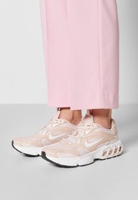 Le sneaker sportive rosa chiaro presentano un design in materiale mesh e sintetico, punta rotonda, logo distintivo e suola testurizzata con ammortizzazione ad aria.