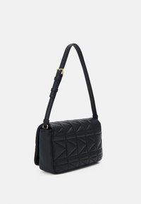 Sac à bandoulière en cuir matelassé noir avec motif géométrique, bandoulière ajustable, ferrures dorées et forme rectangulaire.