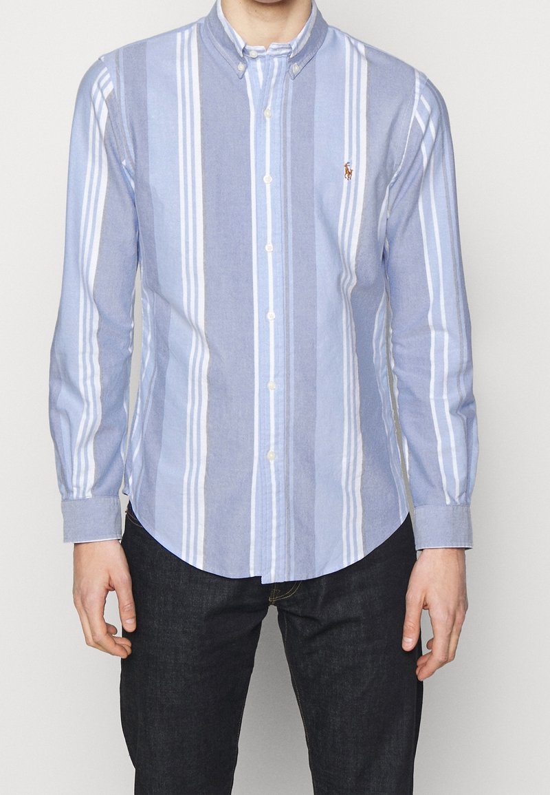 Randig långärmad knäppskjorta i ljusblått och vitt, med krage, europeisk ryggslits och en liten logotyp på bröstet.