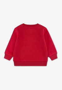 Czerwona bluza z długimi rękawami, ściągaczami przy mankietach i dole, wykonana z miękkiego materiału, z niewielkim kwadratowym detalem na plecach.