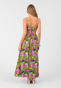 Maxi šaty s živým květinovým vzorem v růžové, zelené a žluté barvě, s tenkými ramínky a zavazováním na zádech; splývavá látka a délka až k kotníkům.