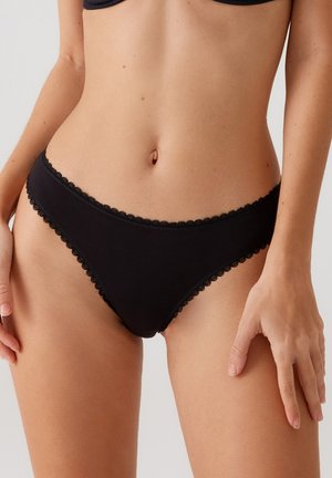 Zwarte katoenen bikini slipjes met een geschulpte kantafwerking langs de randen. De stof lijkt glad en heeft een aansluitend ontwerp.