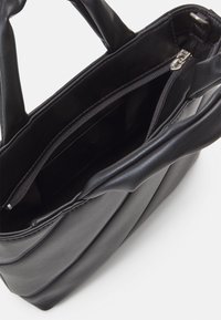Small black leather handbag with double handles and a zippered inner compartment, shown from above on a white surface.