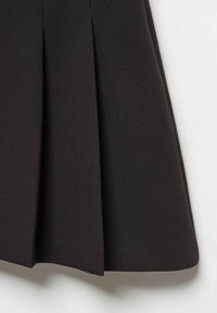 Falda negra plisada hecha de tela suave, con pliegues marcados y un dobladillo limpio, sin cierres ni adornos visibles.