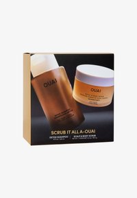 OUAI Scrub It All set bestaande uit een bruine detoxshampoo fles met een witte dop en een ronde, gouden bodyscrub pot met een wit deksel.