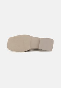 Beige skosåle med en glatt, flat overflate, har en avrundet tå og minimalt mønster for grep. Jevn tekstur over hele.
