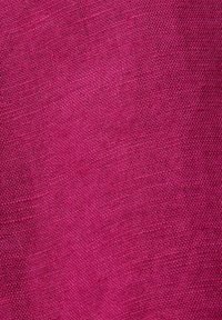 Gros plan d’un tissu magenta tissé serré avec un motif texturé visible et des fils fins.