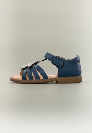 Sandale en cuir bleu marine pour enfant avec plusieurs brides, détail nœud argenté, et bride de cheville ajustable sur un fond gris clair.