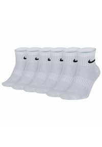 Vita crew-strumpor i bomullsblandning med ribbad textur, med en svart Nike-logotyp på varje strumpa. Sex par uppställda i rad.