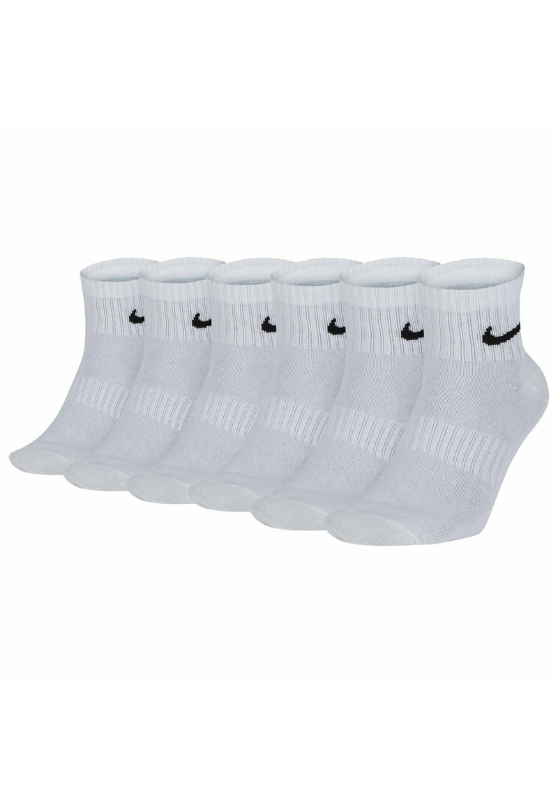 Vita crew-strumpor i bomullsblandning med ribbad textur, med en svart Nike-logotyp på varje strumpa. Sex par uppställda i rad.