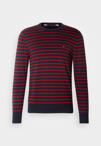 Pull bleu marine à manches longues avec des rayures rouges horizontales et un petit logo sur la poitrine, col rond, poignets et ourlet côtelés.