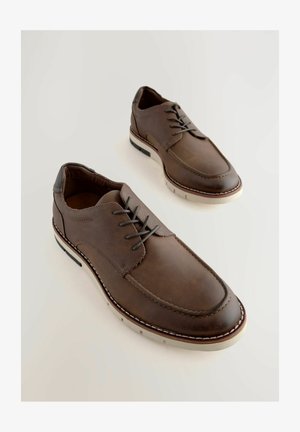 Brązowe skórzane buty o gładkim wykończeniu, z wiązanym fasonem, kontrastującą białą podeszwą i podniesionym przeszyciem wzdłuż krawędzi.