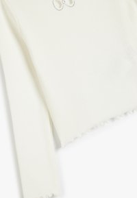 Biała, prążkowana bluzka z długim rękawem z falbaniaszczym dołem i detalem w postaci kryształkowej kokardki z przodu. Miękka tekstura, dopasowany fason.