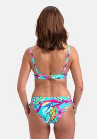 Bikini multicolore con motivo floreale tropicale. La parte superiore ha spalline larghe e una chiusura, mentre la parte inferiore presenta lacci regolabili.