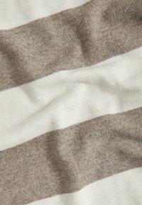 Lekki materiał dzianinowy z szerokimi poziomymi paskami w odcieniach kremowym i delikatnym brązowym. Tkanina ma gładką teksturę z niewielkimi różnicami.