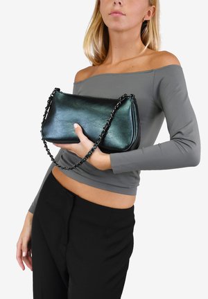 Bolso de mano de cuero negro con una correa de cadena, con un acabado suave y diseño minimalista. Sostenido en una mano contra un fondo liso.