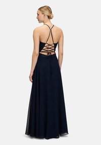 Robe longue bleu marine avec un corsage en dentelle, dos nu avec des bretelles croisées et une jupe fluide.