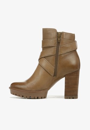 Bruine leren enkelboot met ribbelhak, zijrits en kruislings banddetail. Getextureerde zool voor grip en stabiliteit.