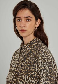 Leopardmönstrad skjorta i mjukt tyg med krage, som har två framfickor och knappstängning. Jordnära nyanser dominerar mönstret.