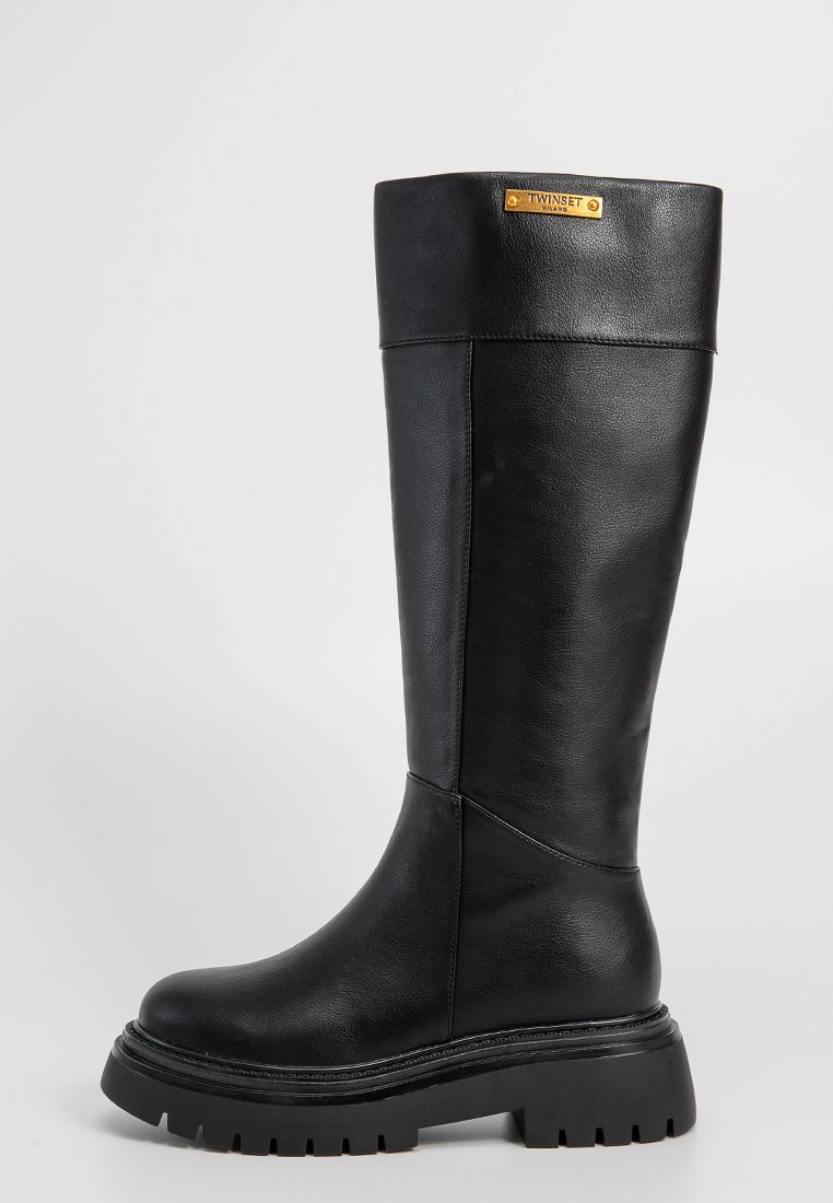 Schwarze knielange Stiefel aus glattem Leder, mit runder Zehenform, chunky Sohle und einem goldenen Etikett am Schaft.