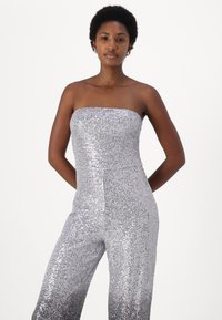 Sølv paljettstrapless jumpsuit med tettsittende overdel og vid buksedesign, med en glatt tekstur og reflekterende overflate.