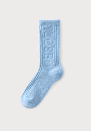 Chaussette bleu clair en tissu éponge avec texture côtelée et texte en relief sur le côté indiquant "CHOSEN" sur un fond uni.