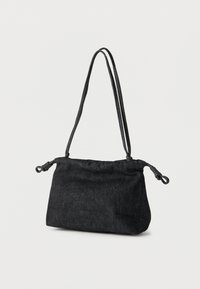 Μικρή μαύρη υφασμάτινη τσάντα ώμου με δύο λεπτούς ιμάντες και δεμένους κόμπους στα άκρα, πάνω σε απλό φωτεινό φόντο.