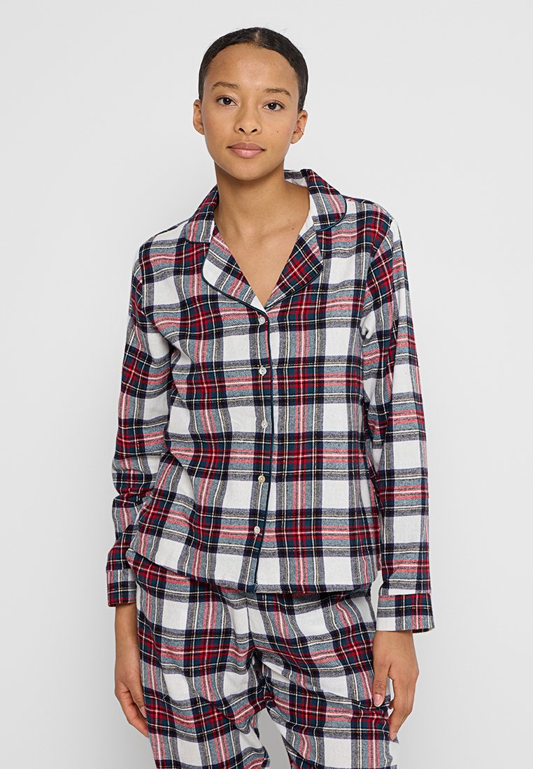 Rutig flanellpyjamas-set i vitt, marinblått, rött och grått. Långärmad skjorta med knappar och krage, matchande byxor med liknande mönster.