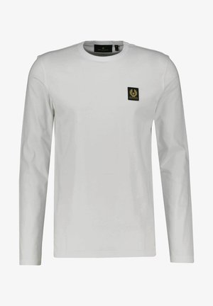 T-shirt de manga longa branca feita de algodão, com um decote redondo e um pequeno emblema preto e dourado no lado esquerdo do peito.