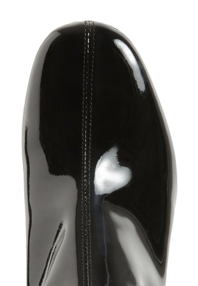 Μαύρη πατέντα δερμάτινη μπότες με κομψή γραμμή, που διαθέτει κεντρική ραφή και γυαλιστερή επιφάνεια. Η μύτη είναι στρογγυλή και λείος.
