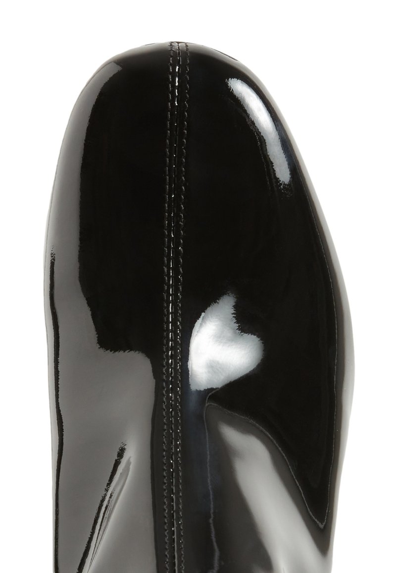 Bota de charol negra con una forma elegante, que presenta una costura central y un acabado brillante. La puntera es redondeada y suave.