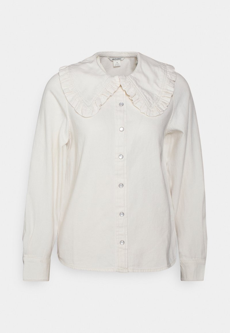 Blouse blanche à manches longues avec grand col à volants et boutons-pression à l'avant, présentée sur fond uni.