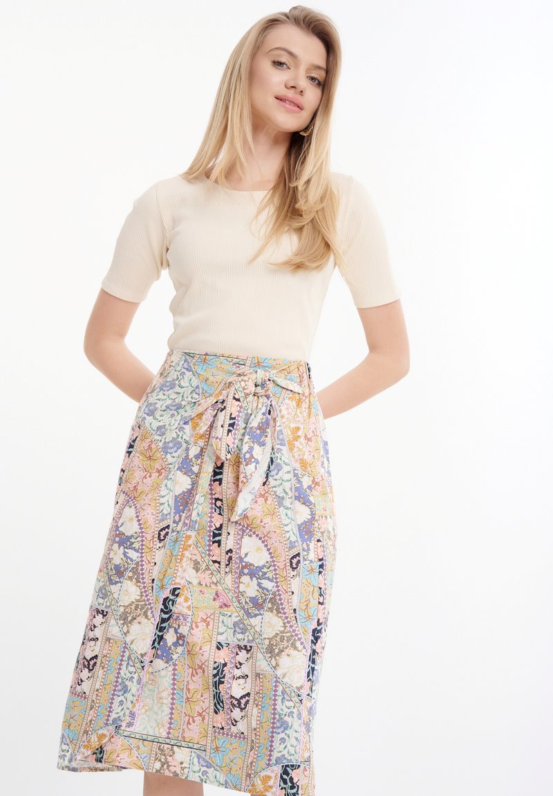 Top corto a maniche corte beige a coste abbinato a una gonna midi multicolore a fiori con vita legata e design fluido.