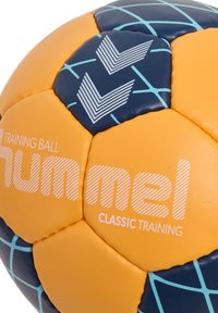 Orange och marinblå träningsboll med en slät yta, blå rutmönster och Hummel-logotyp med vita ränder och logotyp.